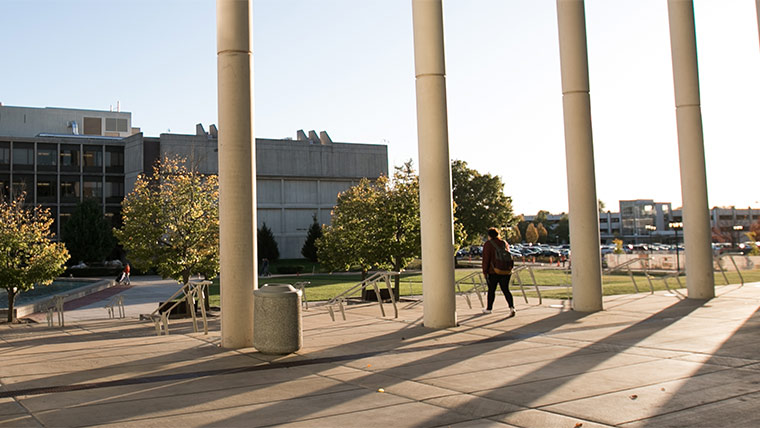 Sun light shines through the pillars at the front entrance of Meyer Library.