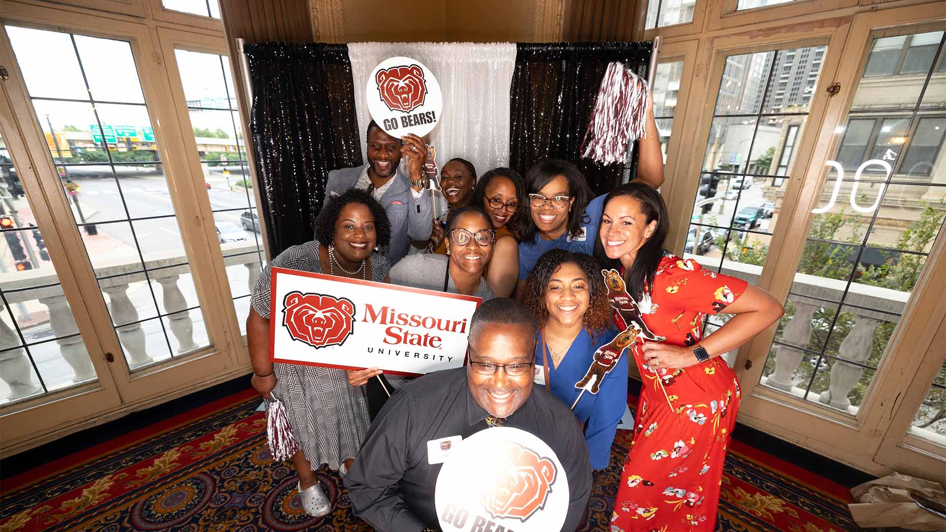 A group of alumni holding up Missouri State signs and posters at an alumni event in St. Louis.