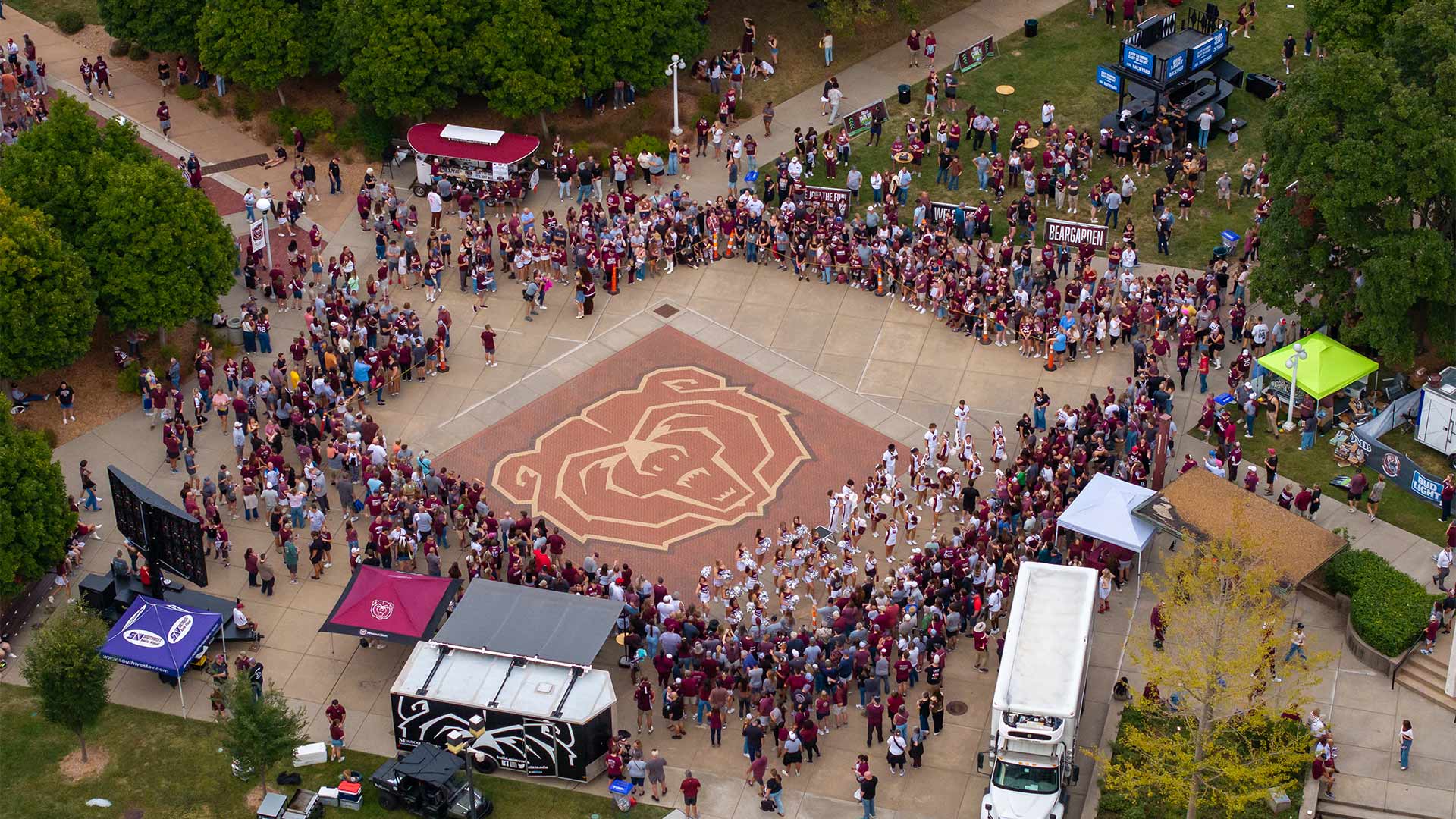 An aerial view of fans and cheerleaders gathered around the maroon Bear head along on the west mall during a pregame tailgate.