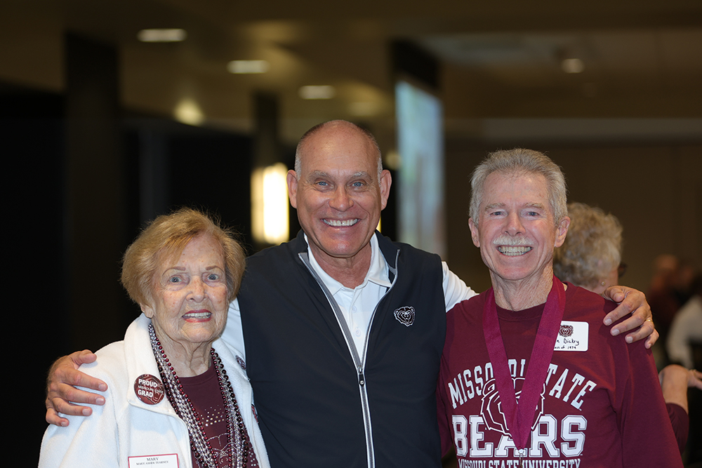 Photo of Three people wearing BearWear standing shoulder-to-shoulder and smiling